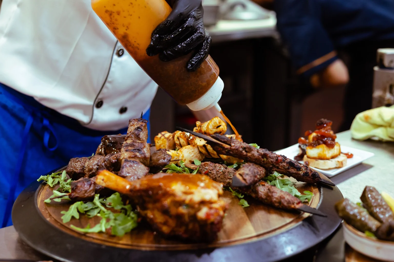 Chef pouring wine beside the Kalimera Feast spread